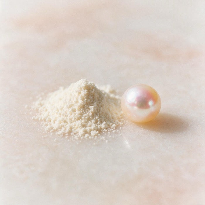 Fine ivory powder beside a single freshwater pearl